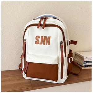 Detail of white and brown contrast backpack with SJM logo on a wooden desk with books