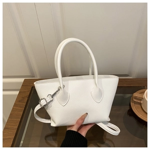 Detail of white lychee textured crossbody bucket bag with silver hardware on wood table