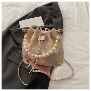 Detailed embroidery on vintage-style bucket bag with pearl handle and floral pattern