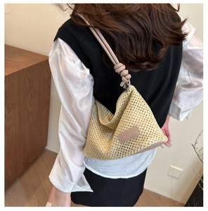 Detail of woven straw shoulder bag with pink leather strap and decorative knot detail