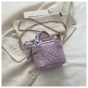 Detail of purple quilted mini bucket bag with silk scarf handle and gold chain strap