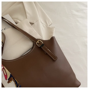 Detail of brown tote bag with white contrast stitching and silk scarf decoration