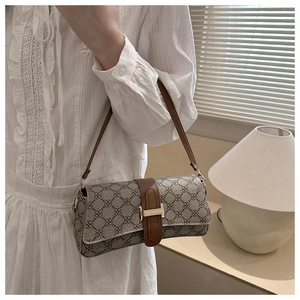 Close-up of a vintage floral print baguette bag with a gold metal H-shaped buckle detail