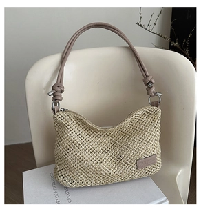 Detail of woven straw shoulder bag with pink leather strap and metallic brand logo