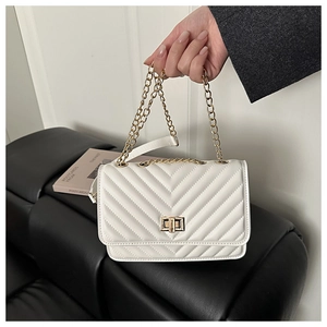 Close-up of white quilted crossbody bag with gold chain strap and twist lock