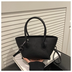 Detail of black litchi texture leather bucket bag with silver metal buckles and top handles