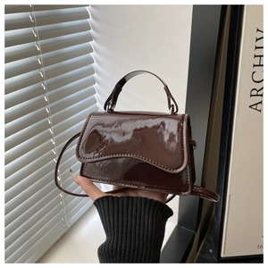 Close-up of brown patent leather mini bag with sleek curved flap and top handle details