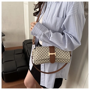 Detail of a chic cream crossbody bag with navy prints and golden H-shaped clasp