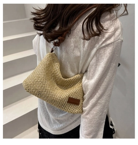 Detail of woven tote bag showing texture, leather shoulder strap and metallic buckle