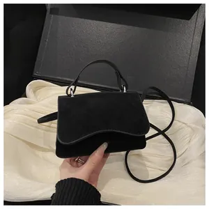 Detail of a black mini square bag featuring wave-edge flap and elegant matte texture