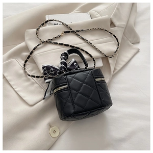Detail of black quilted mini bucket bag with silk scarf handle and golden chain strap
