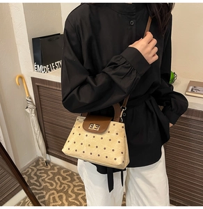 Detail of beige polka dot handbag with brown leather flap and metallic lock closure