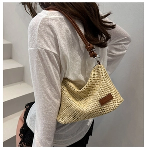 Detail of hand-woven straw bag with leather straps and FANNISSA logo for summer style