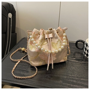 Detail of pink satin bucket bag with gold floral embroidery and pearl handle strap