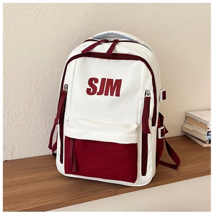 Detail of multi-pocket contrast color school bag with SJM logo on wooden table