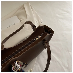 Close-up of brown tote bag with white contrast stitching and decorative silk scarf