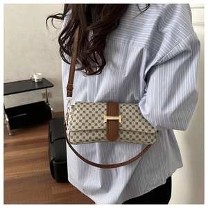 Dettaglio borsa a tracolla con motivo geometrico blu e cinturino in pelle marrone su modella