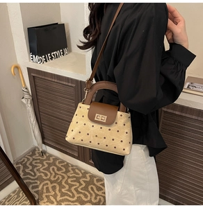 Détail du fermoir tournant doré sur un sac bandoulière vintage à pois pour femme