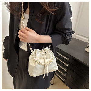 Detail of cream satin bucket bag with floral embroidery and elegant pearl handle