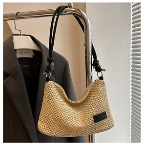 Detail of woven beach tote showing fine straw texture and black leather knot shoulder strap