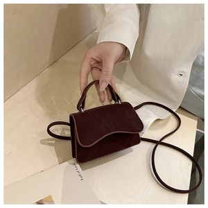 Close-up of wine red mini crossbody bag with wavy flap design and matte leather finish