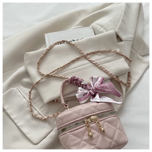 Detailed macro view of pink quilted mini bucket bag with scarf handle and gold chain strap
