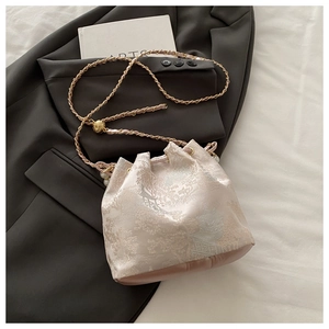 Detail of floral jacquard embroidery on light pink bucket bag with pearl drawstring