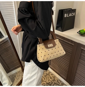 Detail of polka dot crossbody bag with contrast handle and golden swivel lock on model