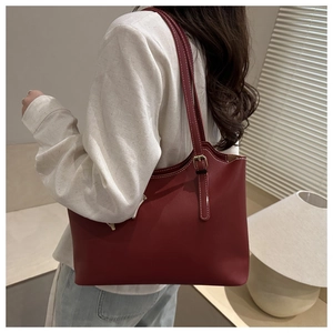 Detailed view of deep red tote bag with contrast stitching and adjustable metal buckle
