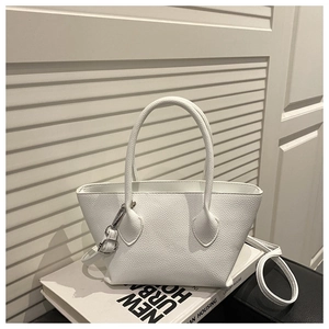 Detailed view of white lychee grain PU leather mini bucket bag on decorative books