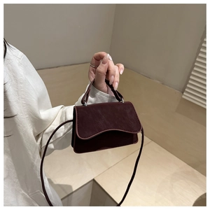 Close-up of a burgundy leather small square bag featuring a unique wavy flap edge design
