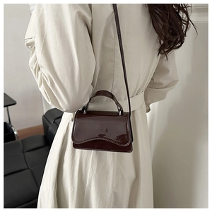 Mirror-finish dark brown patent leather mini bag shown on model for size and fit