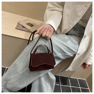 Detail of burgundy retro crossbody bag with wave flap and reinforced handle