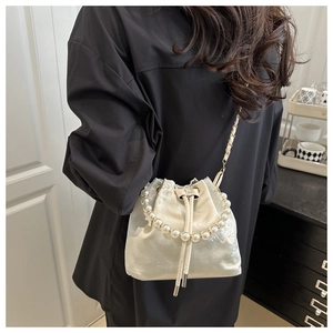 Detailed view of champagne satin bucket bag with floral embroidery and pearl handle