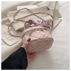 Close-up of pink quilted leather bag featuring floral silk scarf handle and gold chain