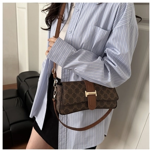 Detail of vintage brown printed shoulder bag featuring a gold metal buckle and leather strap