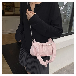 Detail of pink ruched handbag featuring white pearls and a silver metal chain strap