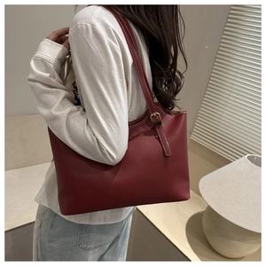 Detail of burgundy tote bag with white contrast stitching and gold buckle on shoulder strap