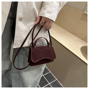 Detail view of mini burgundy crossbody bag with matte finish and wavy flap design