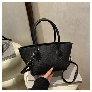 Close-up of black lychee grain leather handbag with fine stitching and metal buckles