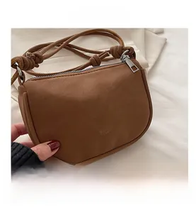 Close-up of brown matte PU leather crossbody bag with metal zipper and strap details
