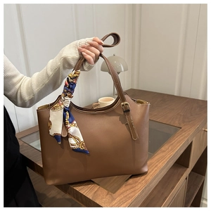 Close-up of caramel brown tote bag featuring decorative silk scarf and stitching