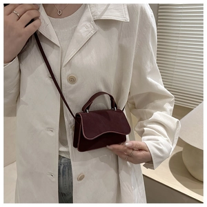 Close-up of a burgundy mini square bag with top handle and strap in home setting