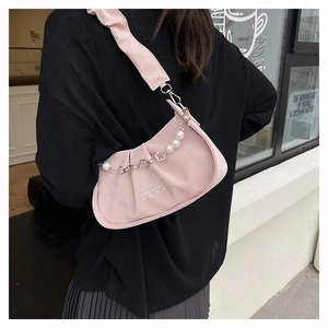 Detail of pink pleated crossbody bag featuring pearl and silver flower decorative chain