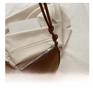 Detail view of smooth silver zipper and knotted strap on dark brown pebble leather bag