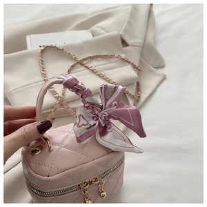Detail of pink quilted mini bucket bag with silk scarf bow and gold chain strap