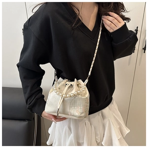 Detail of embroidered satin bucket bag with pearl handle and golden chain strap