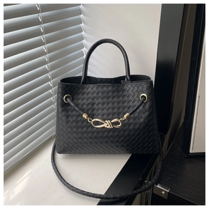 Close-up of black woven leather handbag showing intricate texture and gold metal hardware