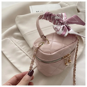 Detailed macro view of pink quilted cylinder bag with silk scarf handle and gold chain