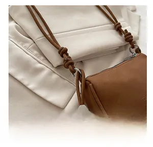 Close-up of brown leather bag showing fine stitching and metal bead with M engraving